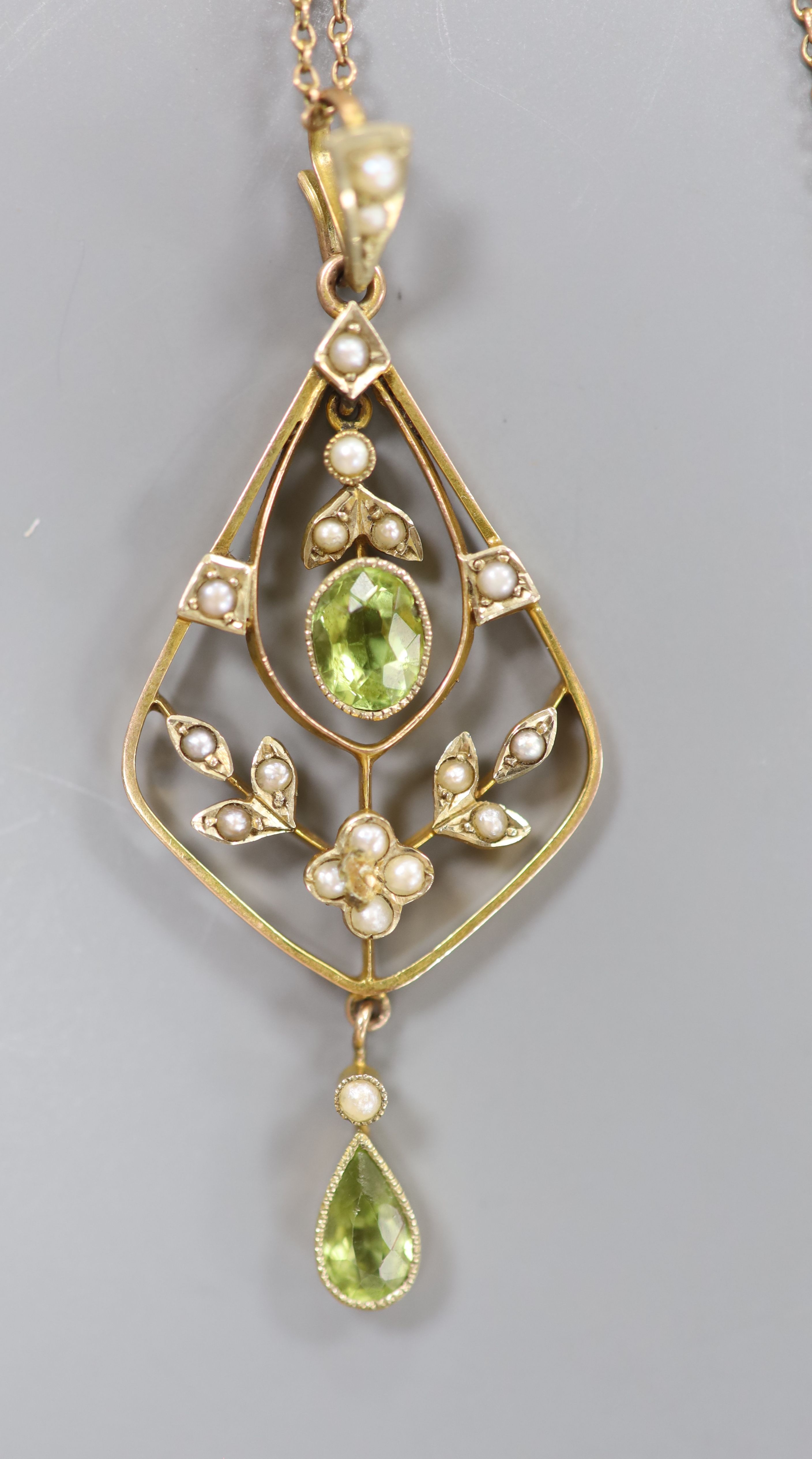 An early 20th century 9ct, peridot and seed pearl set drop pendant, 54mm, on a fine link yellow metal chain, 42cm